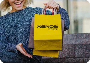 Χάρτινη σακούλα με στριφτό χερούλι και λογότυπο Xenos Packaging, για καταστήματα και takeaway.